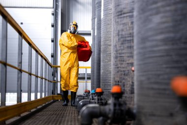 Industrial worker in protective equipment and gas mask working in chemicals factory.