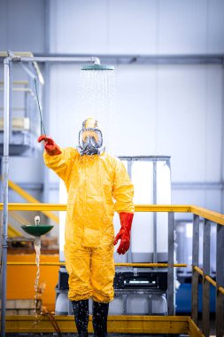 Worker in chemicals production plant taking a shower to wash away the acid after the accident. Occupational health and safety.