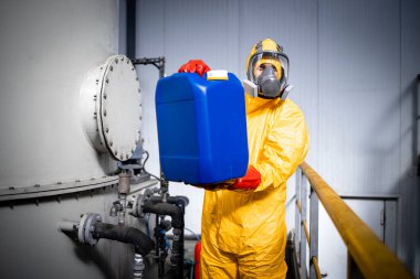 Portrait of worker in zinc galvanizing production plant holding canisters with necessary chemicals and acids.