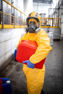 Portrait of chemicals production plant worker in protective suit and gas mask holding plastic can with chemical. clipart