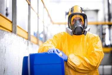 Portrait of worker wearing protection equipment and gas mask working in chemicals production factory.