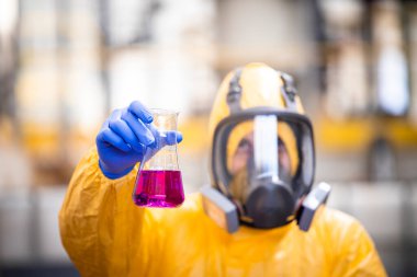 Chemical testing laboratory. Worker in special equipment and gas mask testing quality of chemicals.