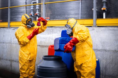 Factory workers testing sulfuric acid. Using protection equipment to avoid severe skin burns and eye damage.