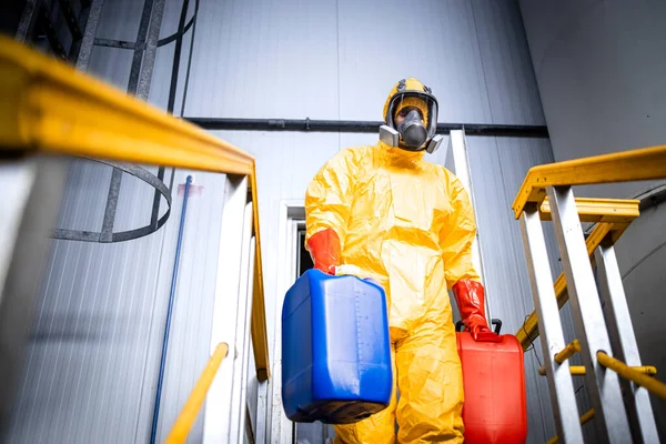 stock image Factory worker wearing protective suit and gas mask carrying chemicals inside industrial production plant.