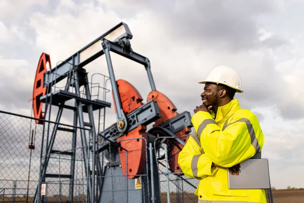 stock image Oil rig worker in protective equipment observing production of crude oil in the field.