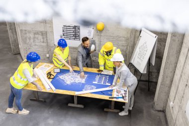 Mimarlar, mühendisler ve işçilerden oluşan deneyimli bir ekip planları ve proje planlarını inceliyor..