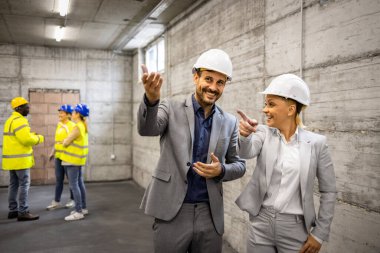 İnşaat alanını ziyaret eden mimar ve yapı mühendisi yeni proje planını tartışıyor.