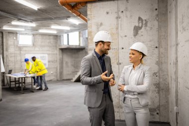 Mimar ve iç mimar inşaat alanını ziyaret ediyor ve yeni proje planı hakkında tartışıyorlar.