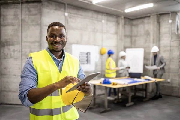 Portrait of African American civil engineer or construction worker holding tablet computer.