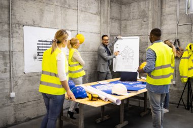 İnşaat mühendisleri ve mimarlardan oluşan bir ekip inşaat sahasında toplanıp inşaatın sonraki aşamasını analiz ediyorlar..