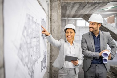 İnşaat alanında birlikte çalışan mimarlar inşaat sürecini kontrol edip teftiş ediyorlar. Proje planına ve planına bakıyorum..