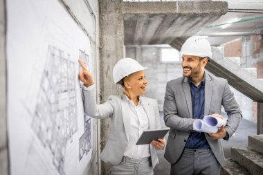 İnşaat mühendisleri inşaat alanında birlikte çalışıp inşaat sürecini kontrol ediyorlar. Proje planına ve planına bakıyorum..