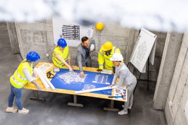 Mimarlar, mühendisler ve işçilerden oluşan deneyimli bir ekip planları ve proje planlarını inceliyor..