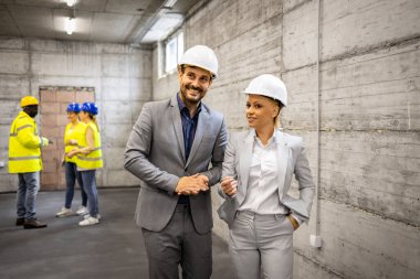 Mimar ve iç mimar inşaat alanını ziyaret ediyor ve yeni proje planı hakkında tartışıyorlar.