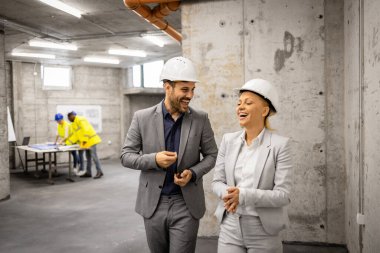 Mimar ve iç mimar inşaat alanını ziyaret ediyor ve yeni proje planı hakkında tartışıyorlar.