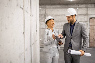 İnşaat işi - mimar ve inşaat mühendisi inşaat sahasında yürüyor ve yeni proje planı hakkında tartışıyorlar