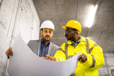 İnşaat işçisi ve inşaat mühendisi planlar ve yeni projeler üzerinde birlikte çalışıyorlar..