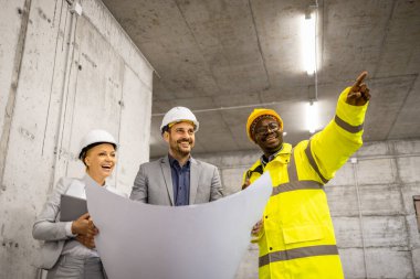 İnşaat mühendisleri ve mimarlardan oluşan bir ekip proje planları tutuyor ve fikirleri görselleştiriyor..