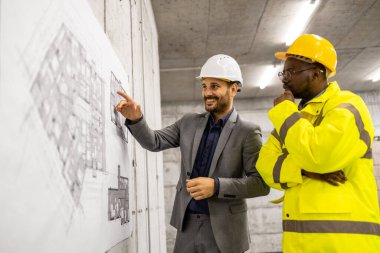 İnşaat mühendisi veya mimar şantiyedeki işçiye bina planı ve planı sunar..