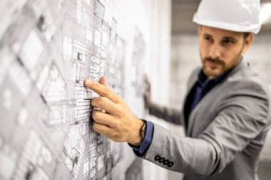 Proje planına ve analizine odaklanmış mimar veya inşaat mühendisi.