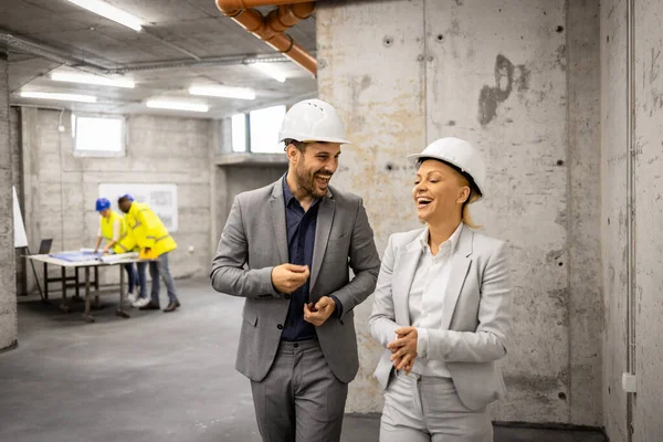Mimar ve iç mimar inşaat alanını ziyaret ediyor ve yeni proje planı hakkında tartışıyorlar.