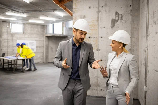 Construction business - architect and civil engineer walking through construction site and discussing about new project plan