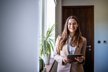 Ofisin penceresinde duran tabletli çekici iş kadını portresi..