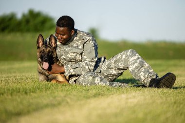 Üniformalı asker askeri köpeğiyle oynaşıyor ve sarılıyor..