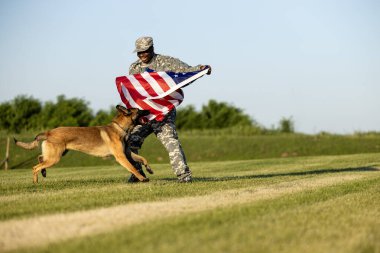 Savaş kahramanları ve gerçek vatanseverler özgürlüğün ve bağımsızlığın tadını çıkarıyorlar. Amerikan bayrağı tutan asker ve asker köpeği.