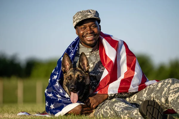 Portrait of true American war heroes. Soldier and his dog covered in USA flag.