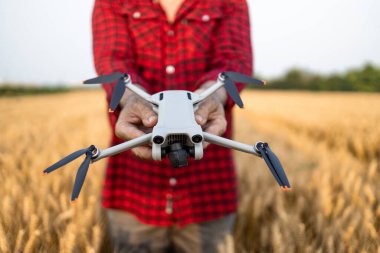 Tarımsal insansız hava aracı taşıyan tanınmayan çiftçinin dosyadaki ekinleri izlediği yakın plan görüntüsü..