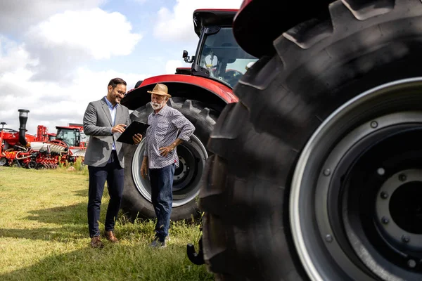 Traktorin Jälleenmyynti Maatalouskoneiden Näyttely Myyjä Viljelijä Keskustelevat Hinnoista Rahoitussuunnitelmista — kuvapankkivalokuva