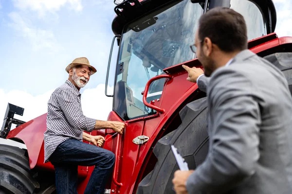 Farmář Vstupuje Nového Traktoru Zatímco Profesionální Prodejce Představuje Kupujícímu Nové — Stock fotografie