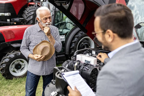 Ammattimainen Traktorin Myyjä Esittelee Uuden Maatalouskoneen Viljelijälle Traktorikoneen Ominaisuudet Moottori — kuvapankkivalokuva