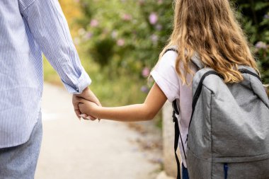 Okulun ilk günü. Ebeveyn ve okul kızı okula giderken el ele tutuşuyorlar..