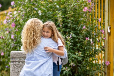 Anne ve kızı okulun önünde birbirlerine sarılıyorlar..