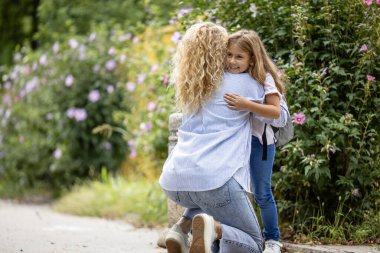 Anne ve kızı okulun önünde birbirlerine sarılıyorlar..