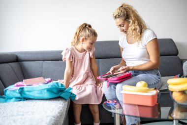Okul için hazırlanıyorum. Anne kızının birinci sınıfa hazırlanmasına yardım ediyor..