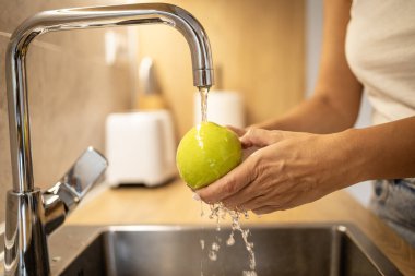 Elma meyvelerinin yıkandığını ve mutfak lavabosuna su sıçrattığını görebilmek için..