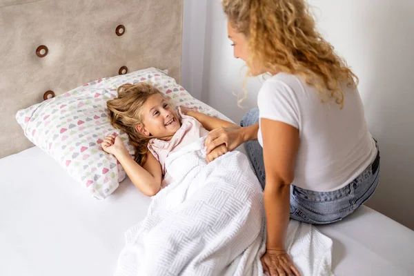 Anne ve kızı yatakta dalga geçiyor. Anne ve babası sabah çocuğunu uyandırıyor..