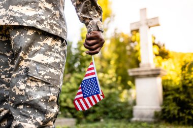 Üniformalı asker, şehit düşmüş savaş kahramanlarının anısına mezarlıkta Amerikan bayrağı taşıyor..