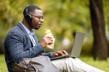 Takım elbiseli bir adam öğle yemeğini yiyor ve internette geziniyor..