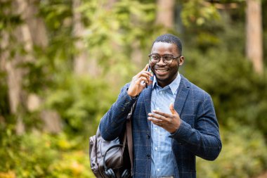 Zarif takım elbiseli bir iş adamı halka açık parkta yürüyor ve telefonda konuşuyor..