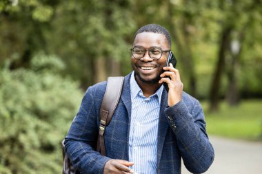 Zarif genç işadamı, sahada yürüyor ve telefonda konuşuyor..