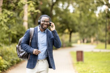 Kulaklıklı, müzik dinleyen, yürürken şarkı söyleyen ve dans eden mutlu bir adam..