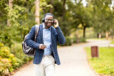 Kulaklıklı, müzik dinleyen, yürürken şarkı söyleyen ve dans eden mutlu bir adam..