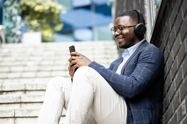 Man in elegant business suit listening music on headphones while having a break.