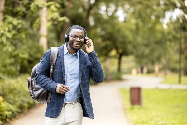 Kulaklıklı, müzik dinleyen, yürürken şarkı söyleyen ve dans eden mutlu bir adam..