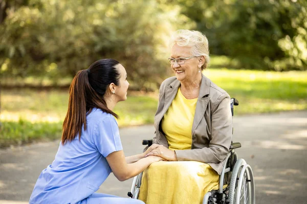 Nursing assistant taking care of elderly woman in wheelchair.