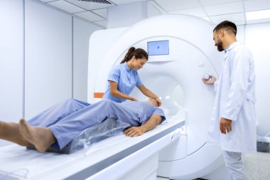 Tıbbi muayene odasında MR çekilirken kıdemli hastaya yardımcı olan kadın doktor..
